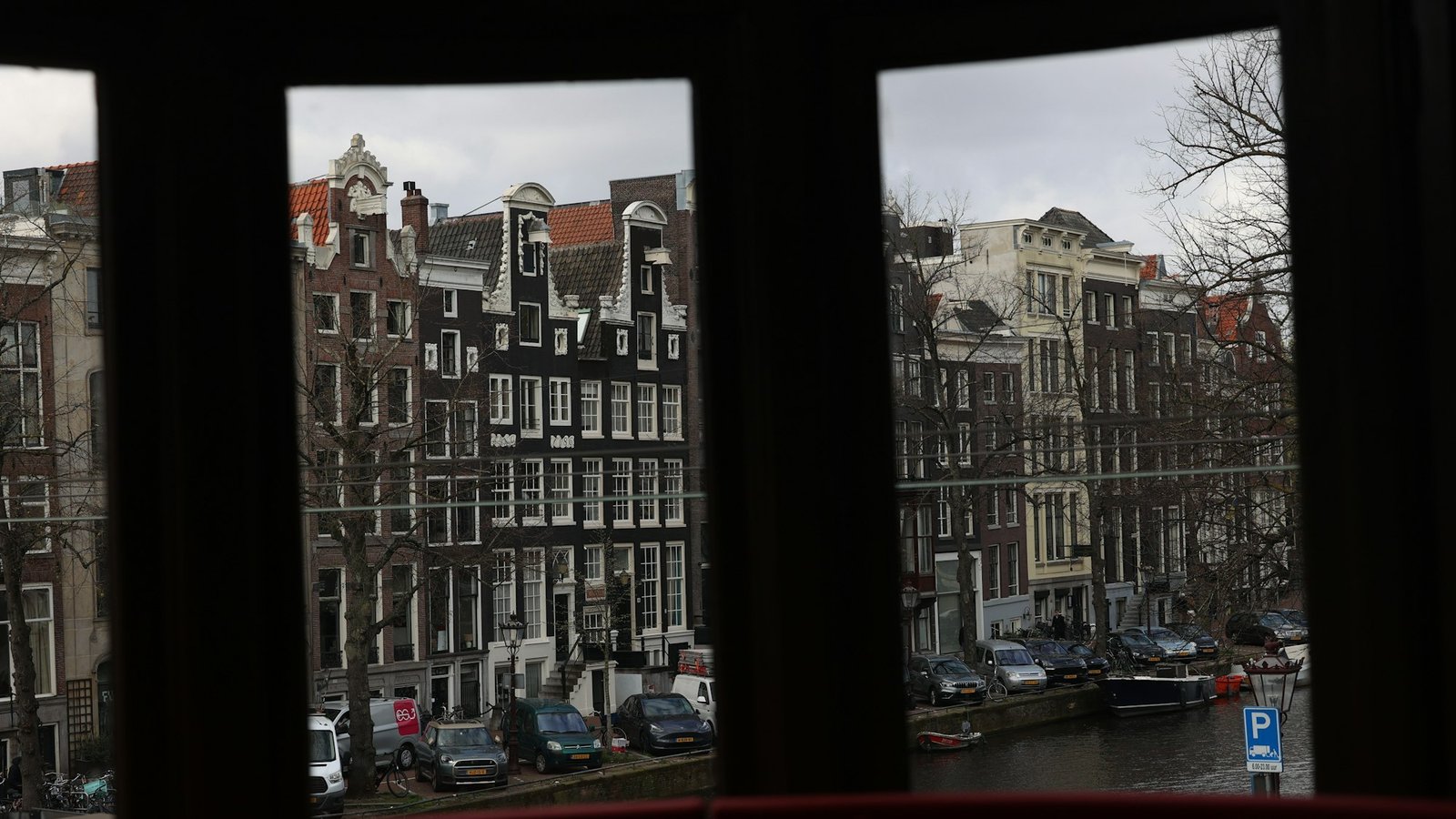Uitzicht vanuit een kantoorraam op grachtenpanden
